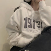 Person wearing a white hoodie with '1973' printed on it